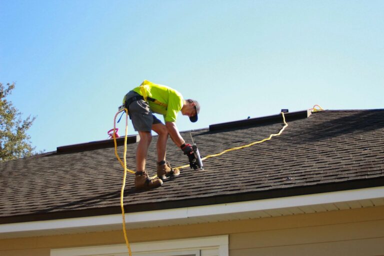 Homeowner examines roof shingles and flashing from a ladder while checking a clipboard.